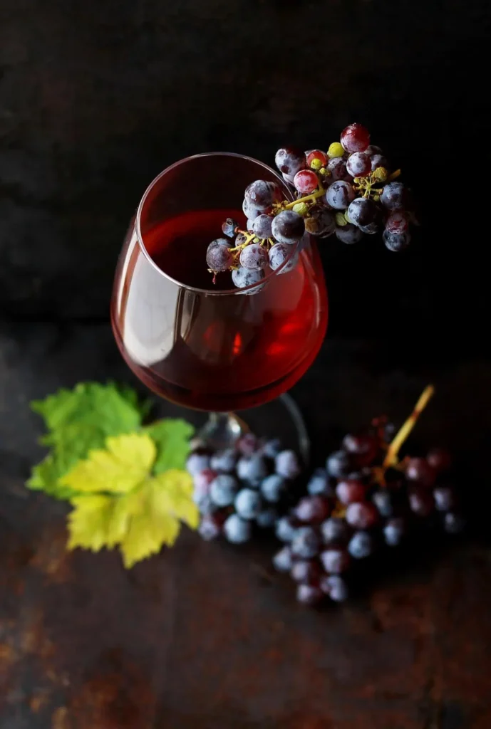 A elegant glass of red wine accompanied by a bunch of fresh grapes, capturing the essence and origins of the wine